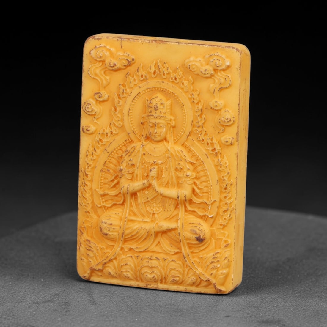 A Chinese Vairocana Deity Carved Tagua Nut Pendant Amulet, 94BC: Carved from tagua nut, this rectangular tablet-form amulet is rendered in high relief. Vairocana Buddha is depicted seated in full lotus posture upon an ornate multi-layered lotus pedestal, hands held