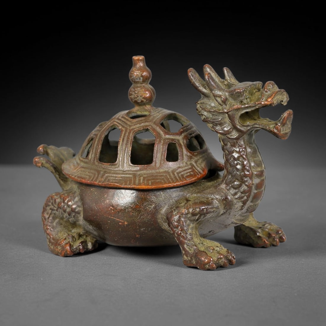 A Chinese Bronze Dragon-Tortoise Form Lidded Censer, 38AD: Cast in bronze, this figural censer is modelled as a mythical dragon-tortoise creature with detailed dragon head, scaled limbs and tortoise-form body. The domed shell-shaped lid features geometric ope