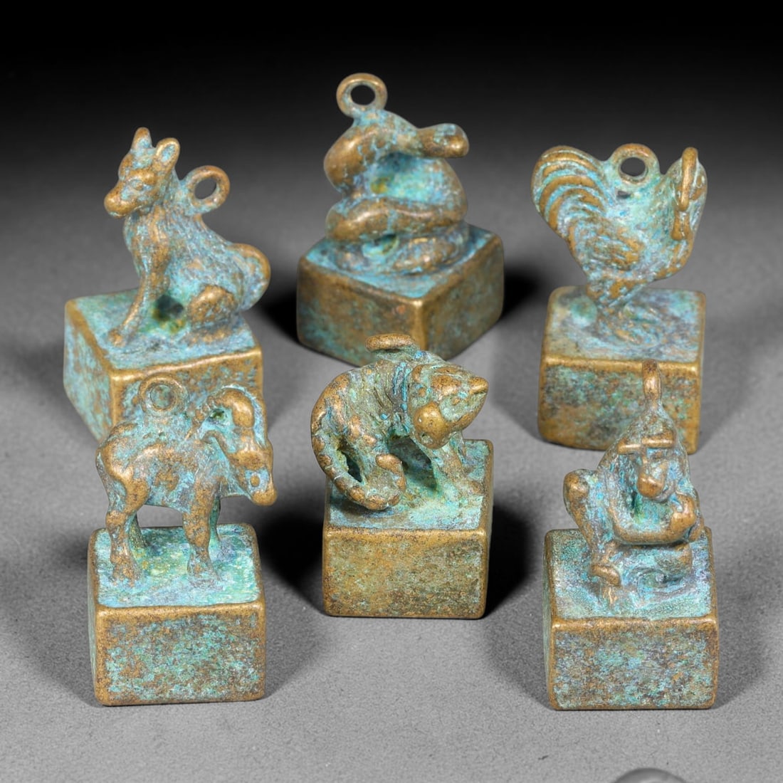 A Lot of Six Chinese Bronze Zodiac Zoomorphic Seals, 14AD: Group of six cast-bronze square-block seals, each surmounted by a finely modelled Chinese zodiac animal knop fitted with suspension loop. Each seal base bears deeply incised archaic seal-script charac