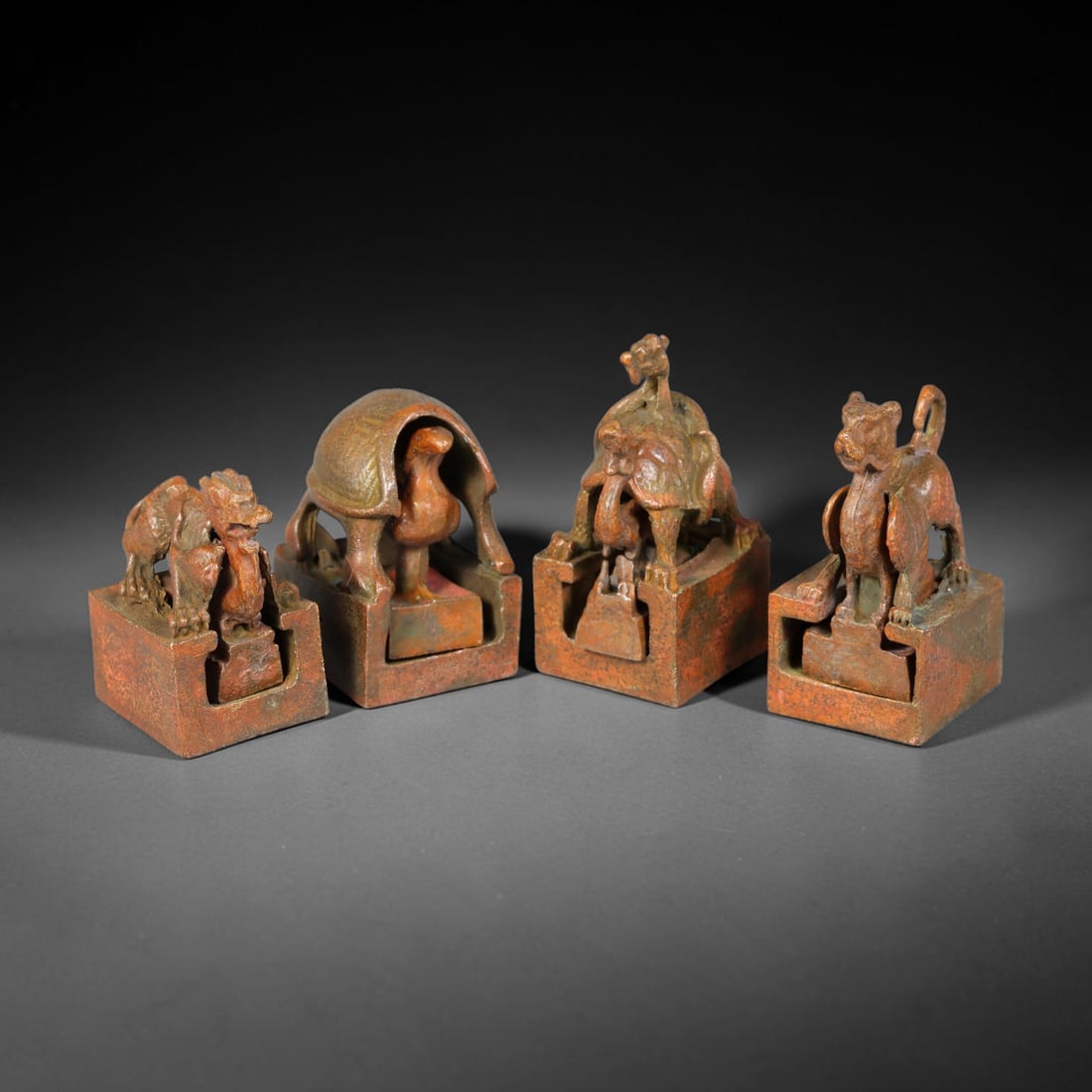 A Lot of Four Chinese Bronze Multi-Tier Mythical Beast Nesting Seals, 27AJ: Group of four composite nesting bronze seals, each consisting of an outer square block surmounted by a symbolic mythical beast finial, housing a smaller nested inner seal with matching animal knop. Re