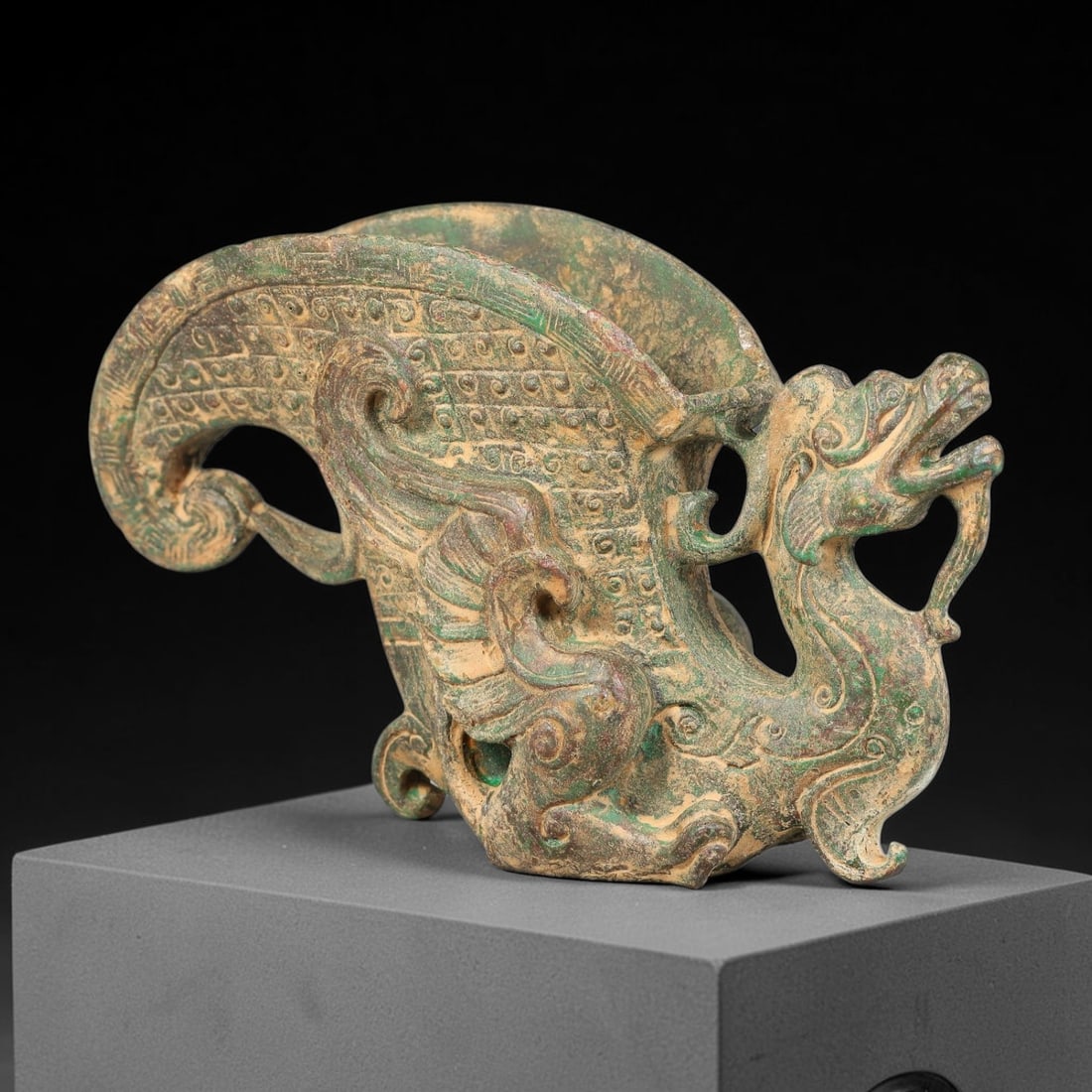 A Chinese Archaic-Style Bronze Dragon-Bodied Rhyton Libation Vessel, 65AD: Cast bronze horn-shaped rhyton libation cup formed around a dynamically coiled dragon figure whose arched neck and head constitute the vessel handle. The curved horn-form cup is densely decorated with