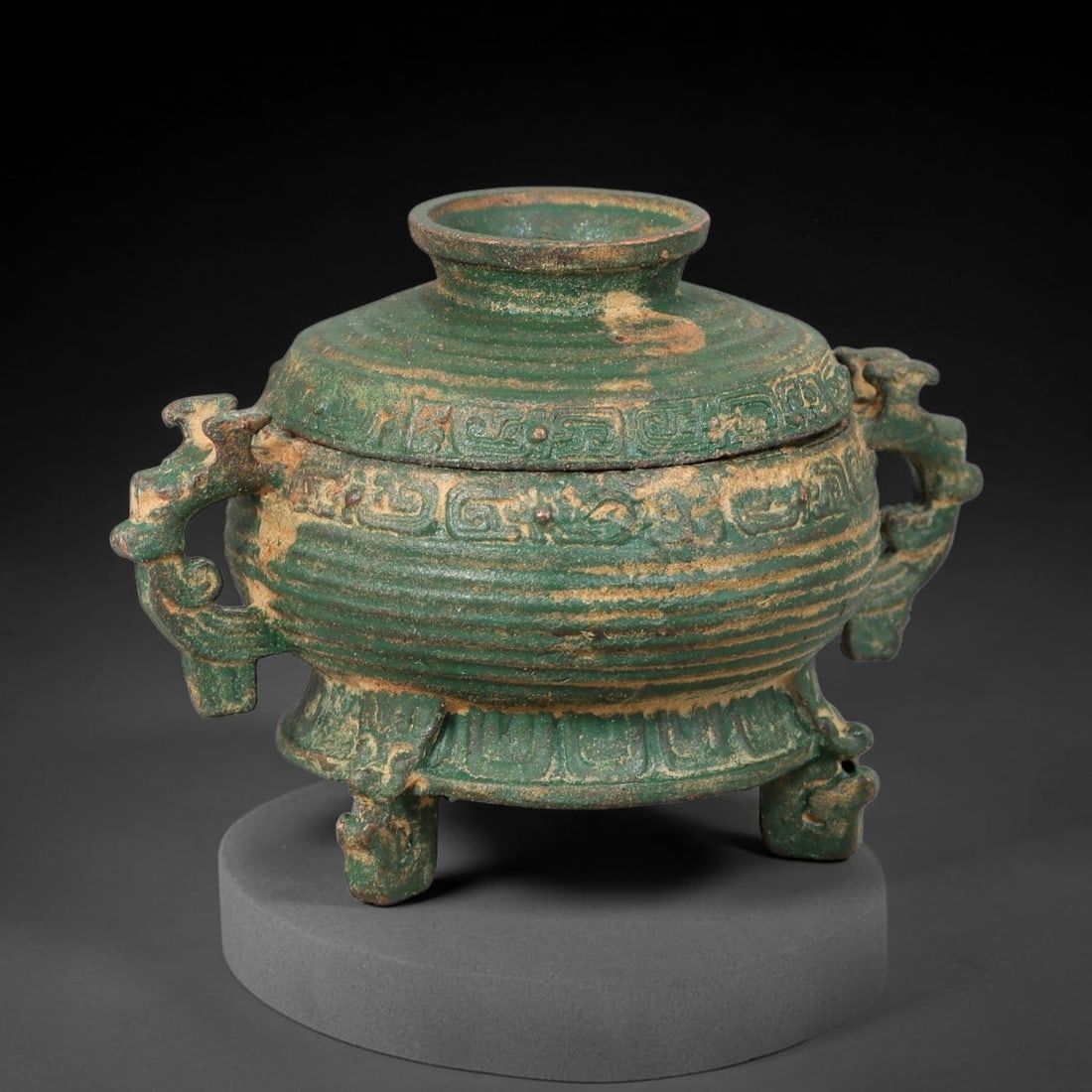 A Chinese Archaic-Style Bronze Lidded Ritual Food Vessel Gui, 53AD: Cast bronze ritual gui vessel with removable domed cover fitted with central knop. The body features horizontal ribbed textures, flanked by two stylized beast-form side handles, and stands upon three 
