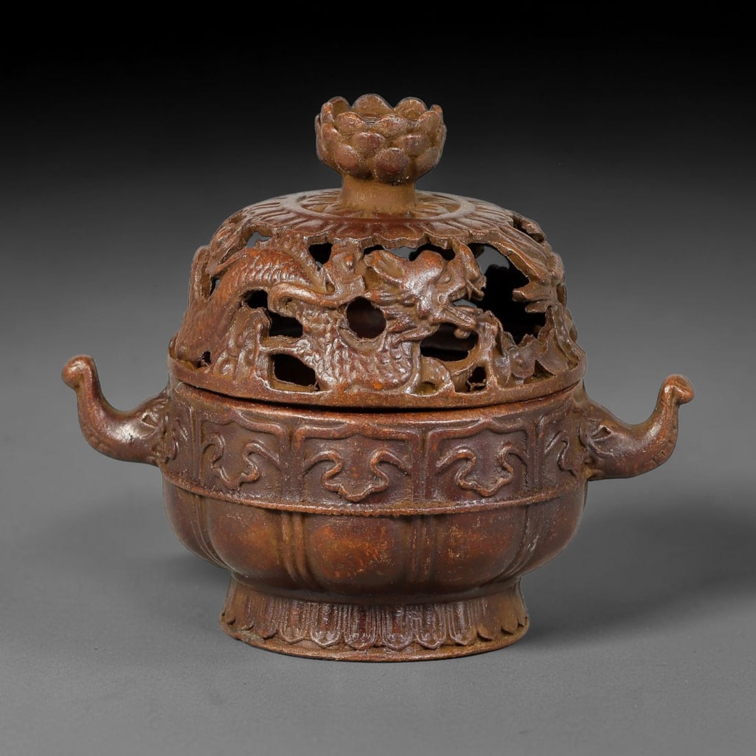 A Chinese Bronze Lobe-Form Censer with Dragon Pierced Lid and Lotus Finial, 90AD: Cast bronze censer of lobed melon shape, fitted with a domed open-work lid carved with writhing dragon amid cloud motifs, surmounted by a full lotus-blossom finial. Two stylized beast-head side handle