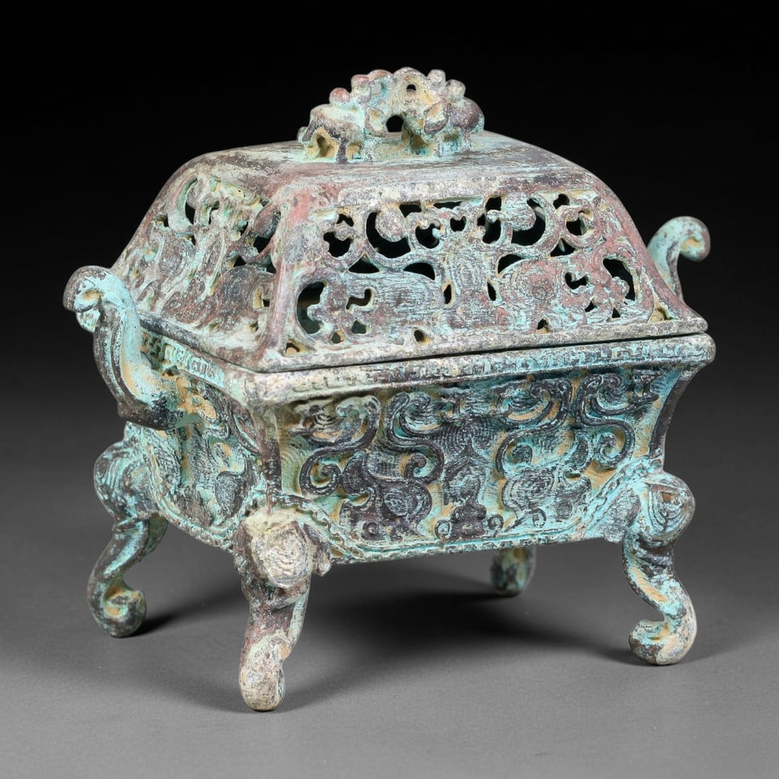 A Chinese Open-Work Square Bronze Censer with Dragon Finial, 75AD: Cast bronze square-form censer fitted with a pierced open-work lid crowned by an intertwined dragon-style finial for smoke dispersion. The body is decorated in high relief with scrolling mythical beas