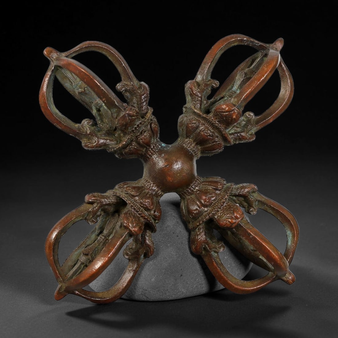 A Chinese Tibetan Bronze Four-Pointed Double Vajra, 13AJ: Cast in bronze, this cross-shaped four-pointed double vajra features a central spherical hub, with each terminal formed as an ornate multi-pronged vajra head decorated with fine lotus foliate carvings