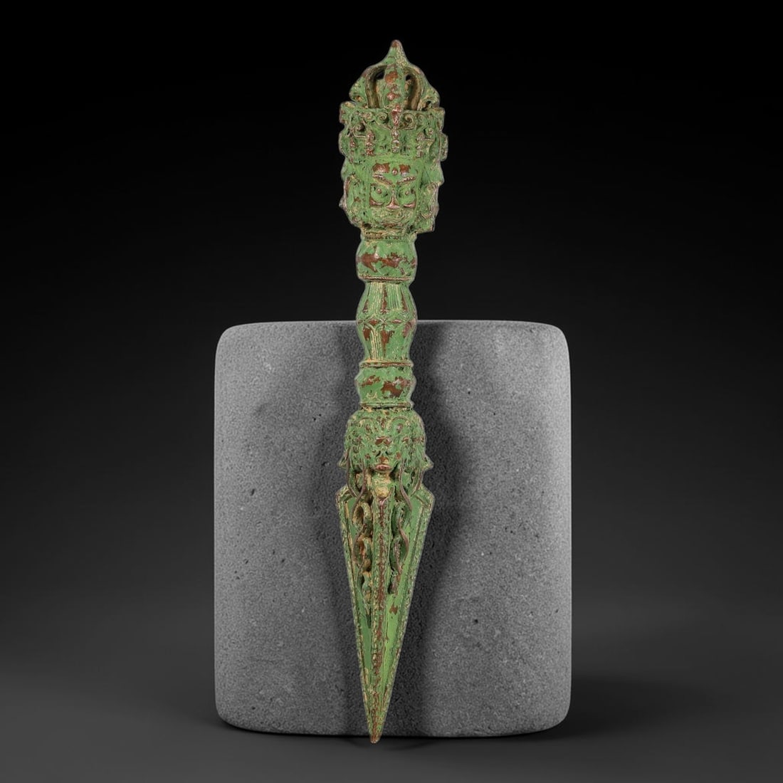 A Chinese Tibetan Bronze Multi-Headed Phurba Ritual Dagger, 69AD: Cast in bronze, this ceremonial phurba features multiple carved wrathful deity heads at the upper finial surrounded by elaborate open-work foliate ornament. The segmented handle exhibits layered mould