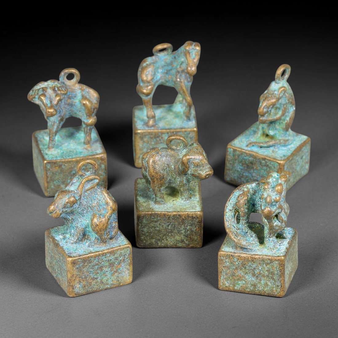 A Lot of Six Chinese Bronze Zodiac Zoomorphic Seals, 17AD: Group of six cast-bronze square-block seals, each surmounted by a finely modelled Chinese zodiac animal knop fitted with suspension loop. Each seal base bears deeply incised archaic seal-script charac