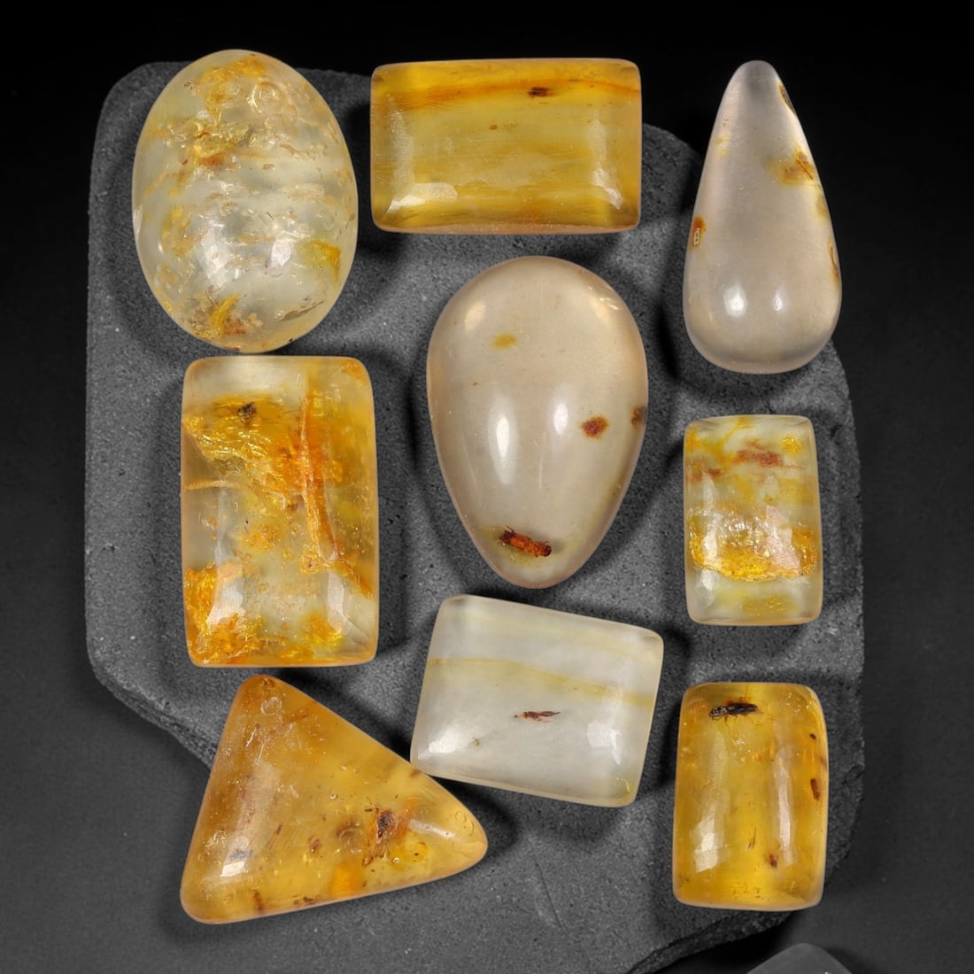 59.98ct Natural Baltic Amber Polished Cabochon Parcel Lot, 29AJ: This parcel features rounded rectangle cabochon baltic amber pieces with warm translucent golden-yellow to honey-gold tones. Smooth polished domed surfaces expose numerous preserved small insect fragm