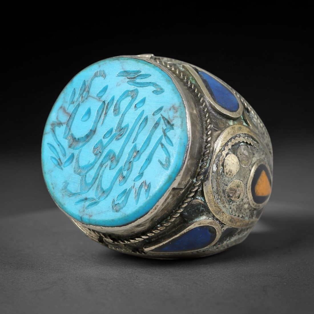 Vintage Islamic Handcrafted Silver Plated Calligraphic Talisman Statement Ring, 42AJ: This vintage hand-wrought Islamic statement ring features a central engraved panel bearing traditional calligraphic detailing, set within an ornate silver-plated metal band. The mounting is enriched w