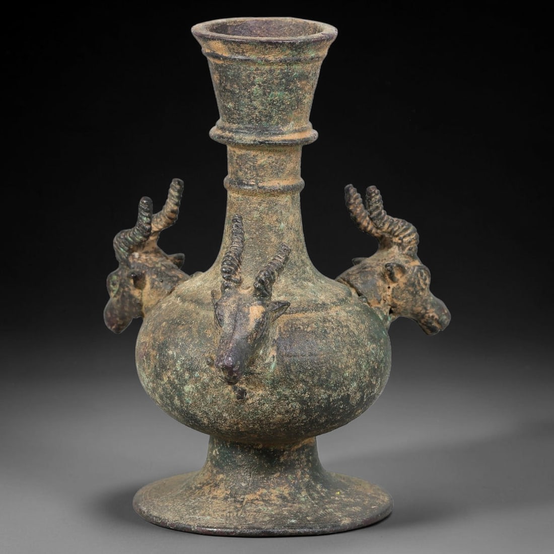 Ancient Seljuk Period Bronze Three-Ibex-Head Vessel (11-13th Century CE), 33AJ: Medieval Islamic bronze vessel of Seljuk cultural origin, bulbous rounded body rising to stepped neck and flared mouth, supported by wide flaring foot base. Three fully modelled ibex heads with detail