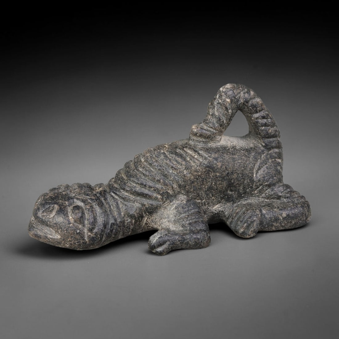 Ancient Sasanian Persian Schist Crouching Feline Talisman (224-651 CE), 70AJ: Carved dark schist stone talisman depicting a crouched predatory feline creature, rendered in characteristic Sasanian zoomorphic artistic style. Deep incised striations define the musculature and patt