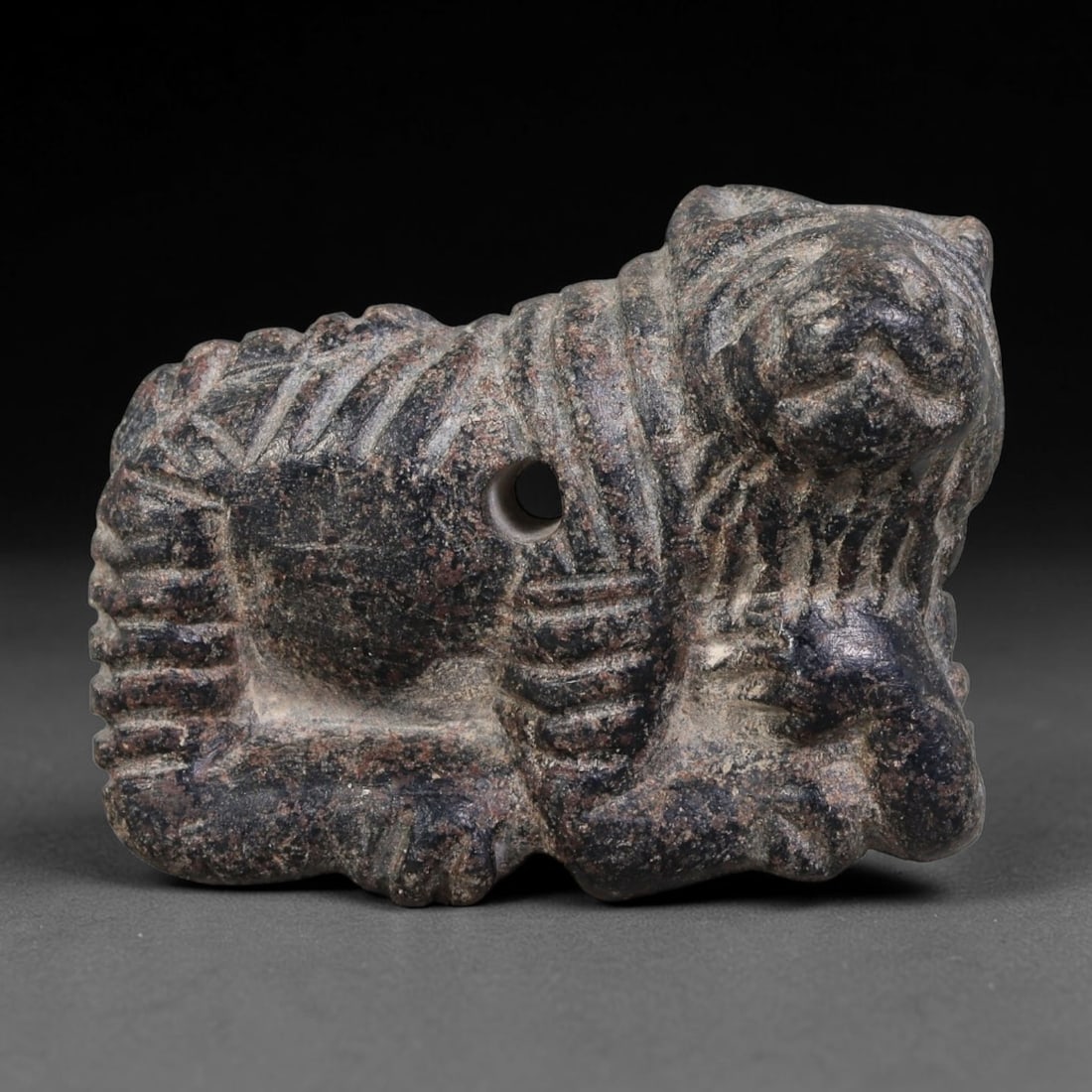 Ancient Assyrian Civilization Recumbent Lion Stone Amulet (2500-609 BCE), 27AK: This miniature carved stone recumbent-lion amulet originates from the Assyrian Civilization of Northern Mesopotamia, crafted as a potent protective talisman reflecting Assyrian royal iconography of li