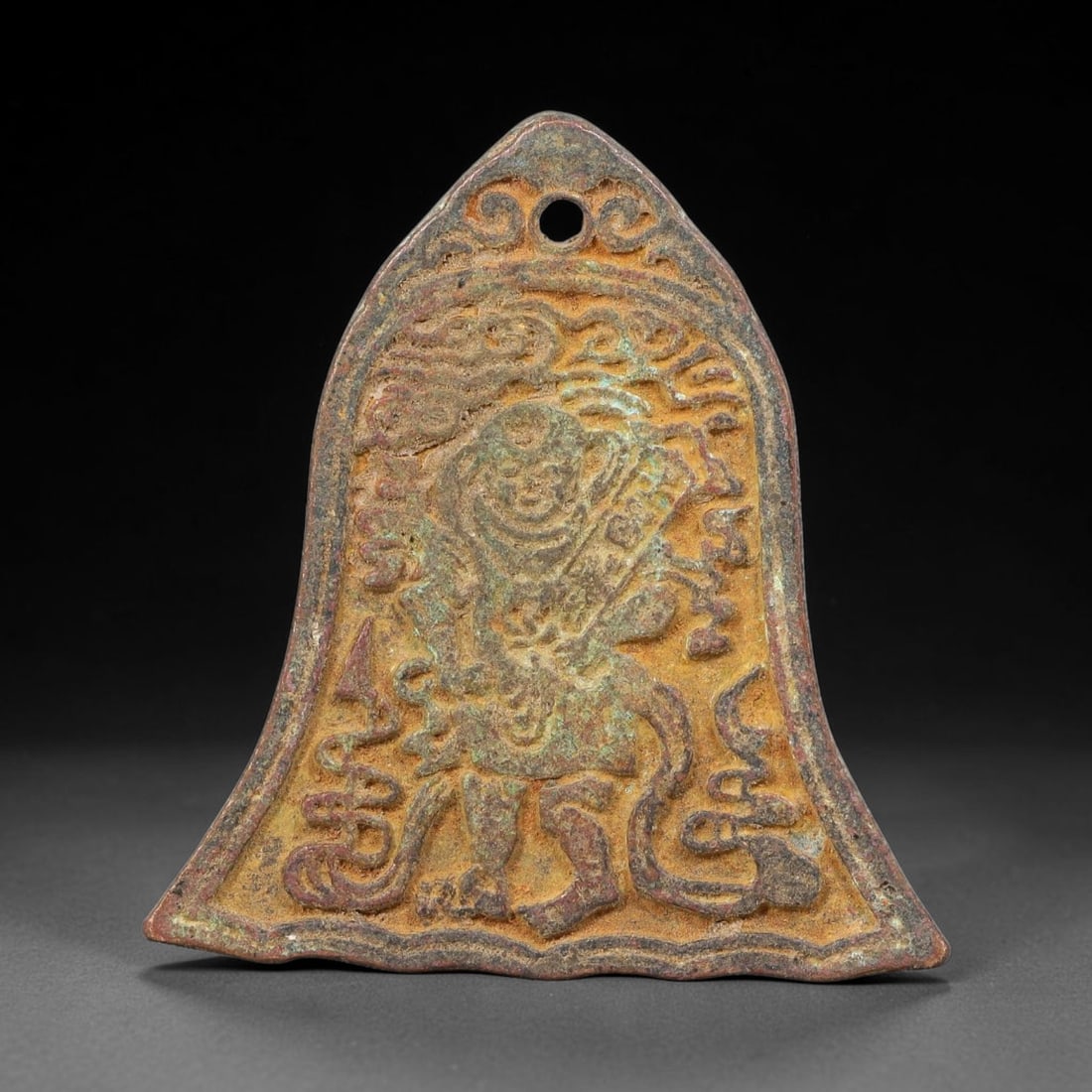A Chinese Bell-Shaped Bronze Protective Amulet Plaque, 42AD: Cast bronze bell-form hanging amulet plaque with pierced suspension hole at the apex. Obverse displays high-relief warrior-like figure amid cloud and scroll ornament; reverse bears central rectangular