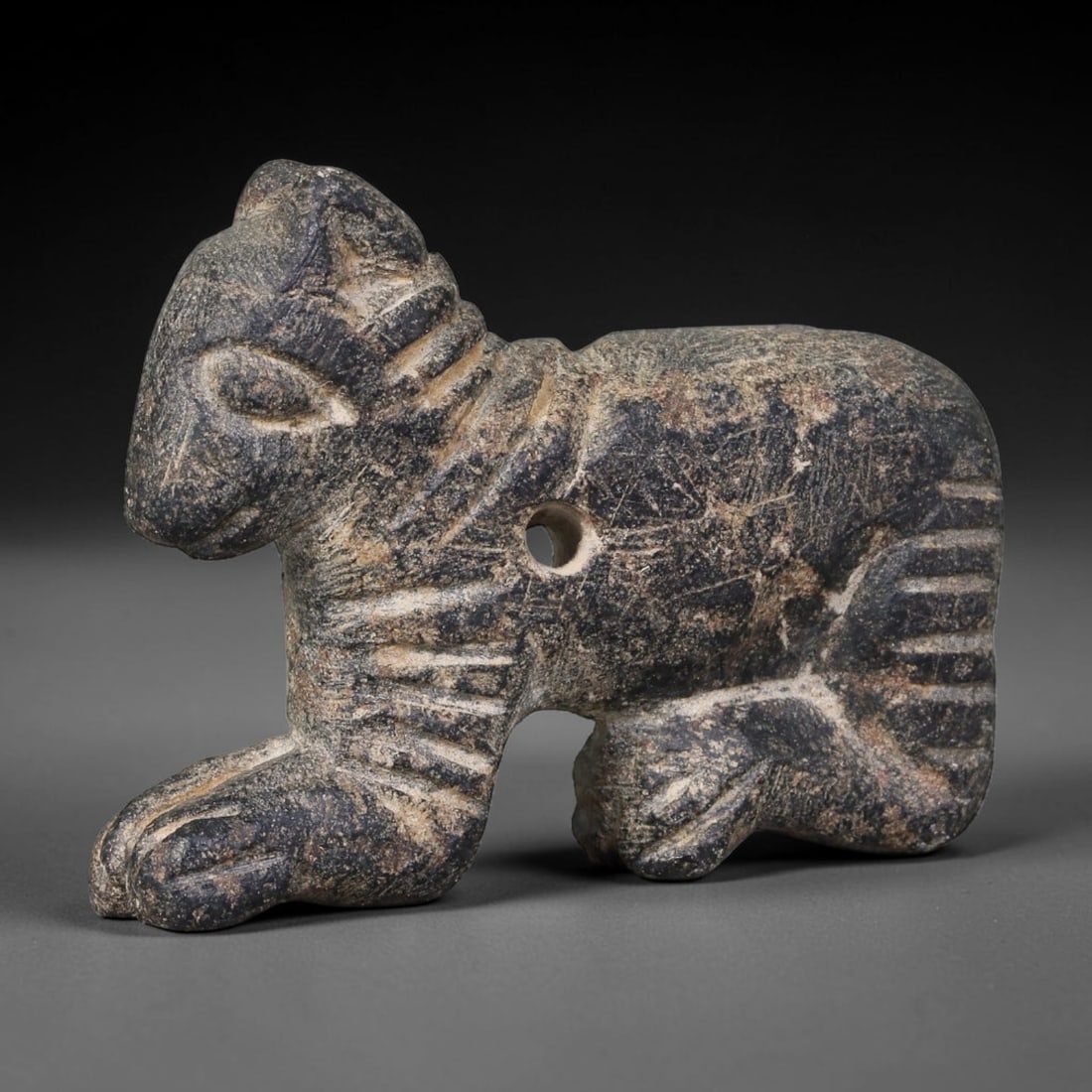 Ancient Assyrian Civilization Crouching Feline Stone Amulet (2500-609 BCE), 12AK: This carved dark stone crouching feline amulet originates from Assyrian Civilization of Northern Mesopotamia, serving as a protective personal talisman embodying the cultural symbolism of strength and