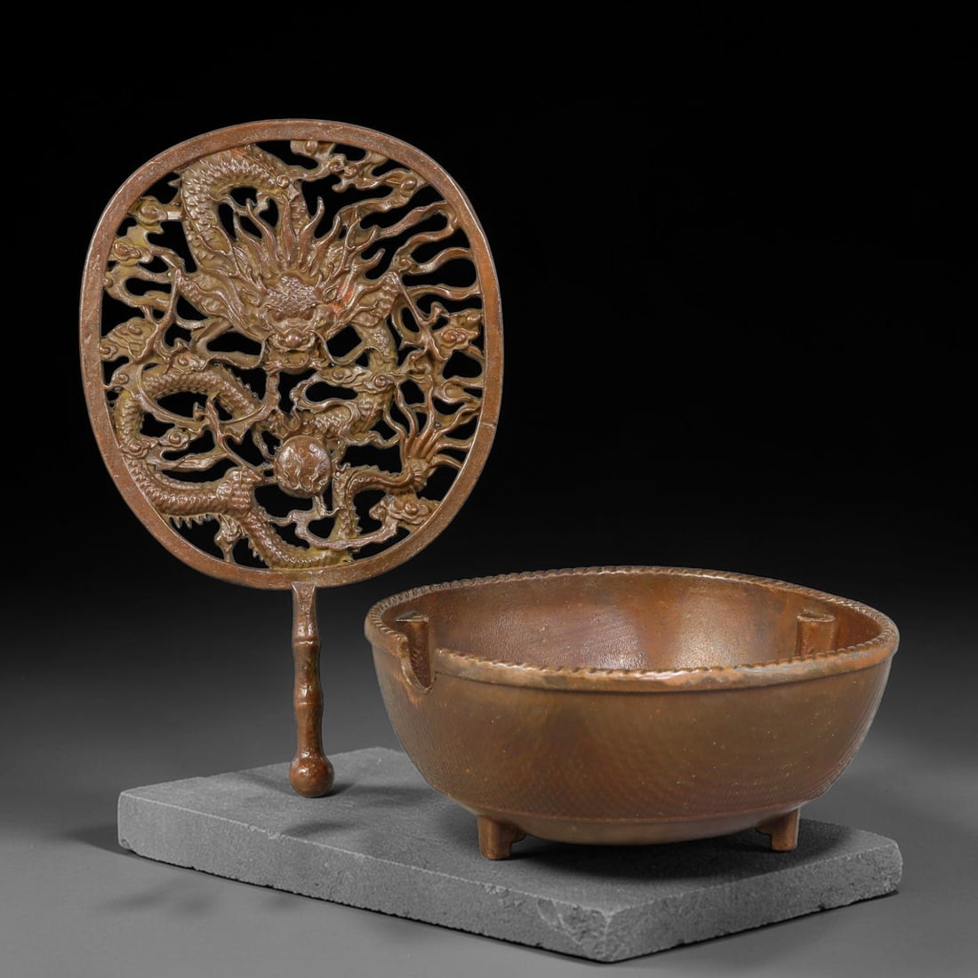A Chinese Bronze Censer with Pierced Dragon-Motif Handled Cover, 17AJ: Cast bronze censer with small tripodal feet and braided-pattern rim, accompanied by a separate handled pierced cover. The cover features elaborate open-work relief depicting coiled dragons pursuing a 