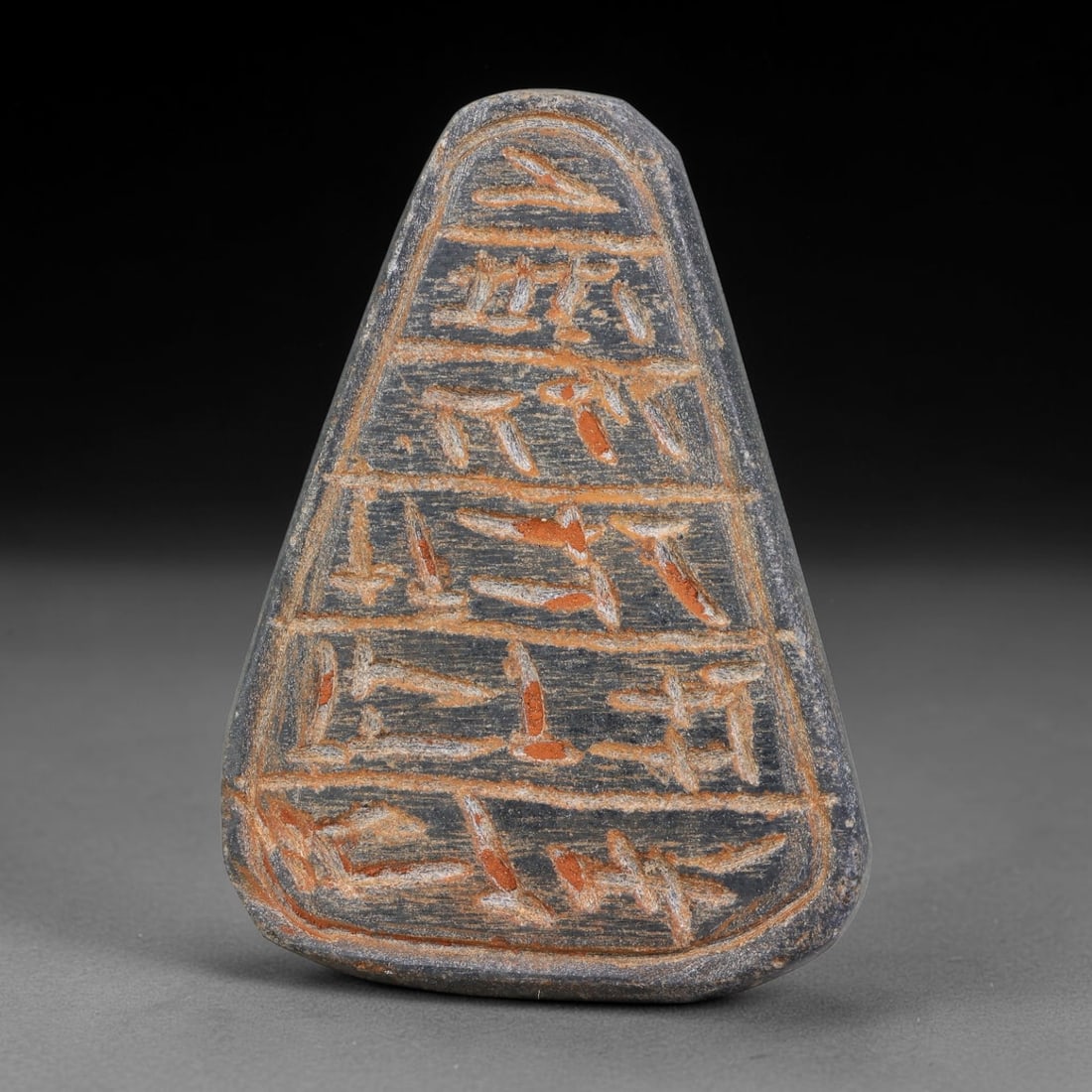 Ancient Uruk Period Triangular Inscribed Apotropaic Amulet (c.3500-3100 BCE), 11AK: Triangular tapered apotropaic amulet originating from the Uruk cultural sphere, its front surface partitioned into horizontal registers bearing deeply incised archaic symbolic script. Distinct reddish