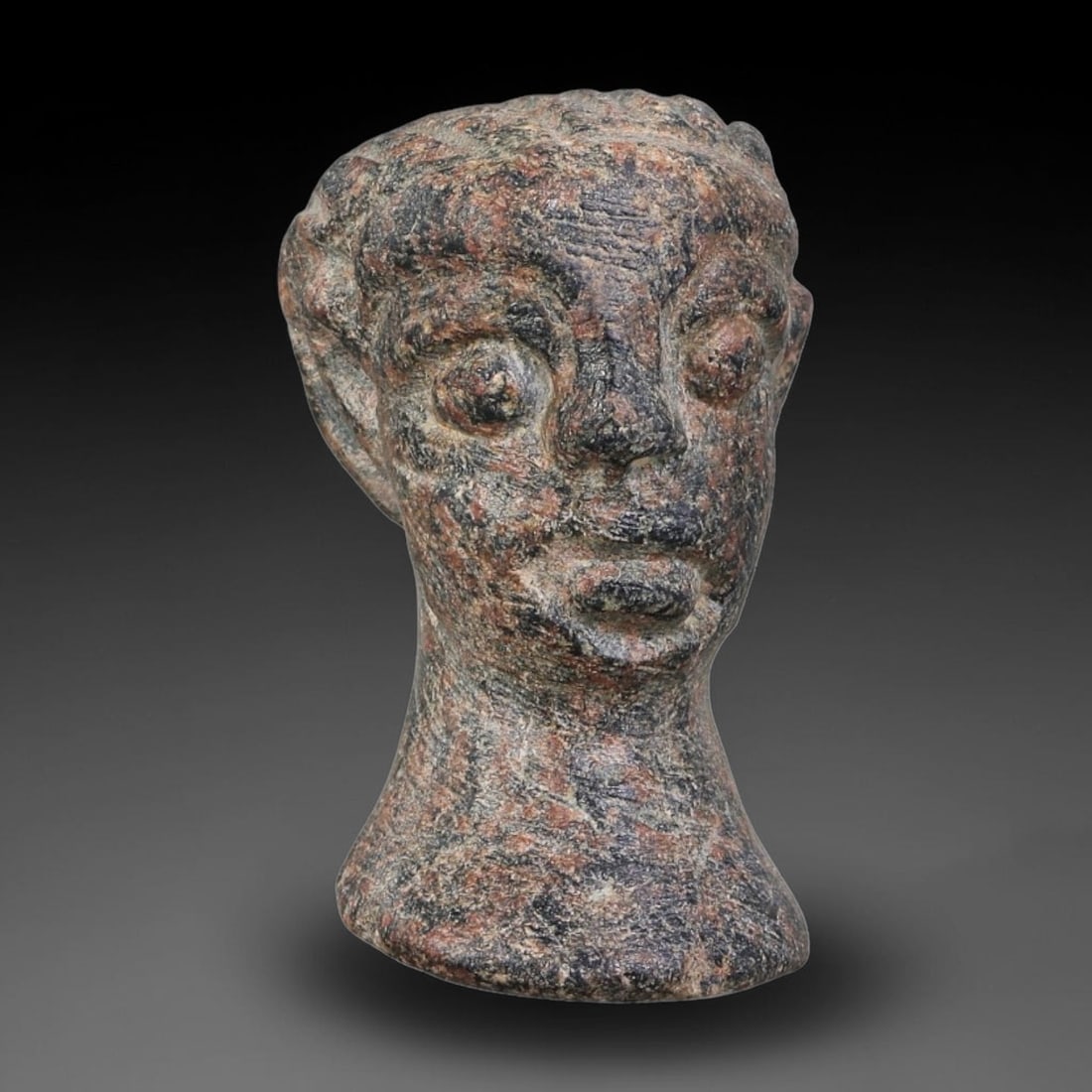 Ancient Elamite Civilization Carved Stone Votive Head (3200-539 BCE), 80AJ: This miniature carved stone votive head originates from Elamite Civilization, rendered with stylized facial features and simplified coiffure. The bust-form fragment exhibits characteristic Near Easter