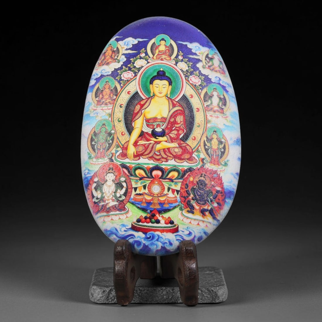 A Tibetan Thangka Style Painted River Stone with a Buddhist Figure, 70BC: Painted on a naturally rounded river stone, the work depicts a seated Buddhist figure in a thangka-style composition. The central figure is shown in a meditative posture, surrounded by protective deit