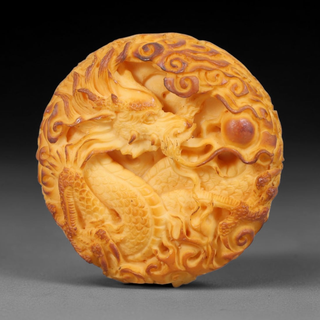 A Chinese Dragon And Phoenix Double-Sided Carved Tagua Nut Pendant Amulet, 91BC: Carved from tagua nut, this circular double-sided pendant features deep pierced high-relief carving. One side depicts a powerful coiled dragon amid swirling cloud scrolls pursuing the flaming pearl, w