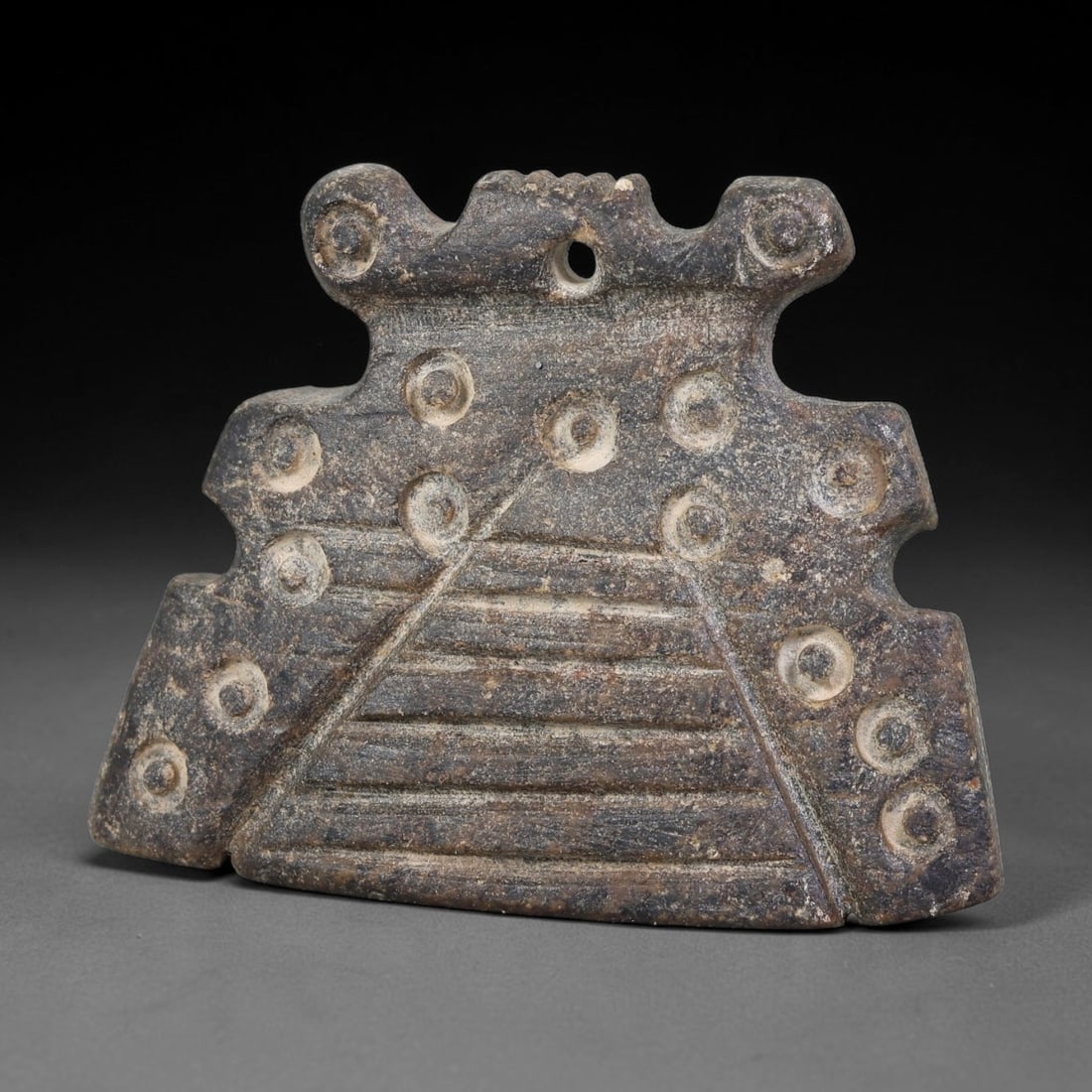 Ancient Elamite Civilization Geometric Decorated Stone Pendant Amulet (3200-539 BCE), 21AK: This flat carved dark stone pendant amulet originates from Elamite Civilization, featuring characteristic Elamite circle-and-dot motifs paired with incised linear geometric ornamentation across its su
