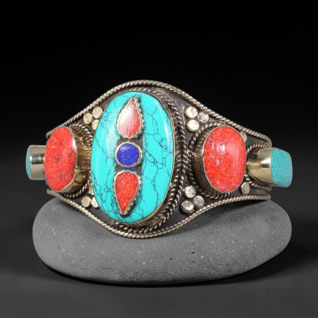 A Tibetan Copper-Alloy Multi-Stone Inlay Cuff Bracelet, 46AK: Crafted in copper-alloy, this cuff bracelet is set with multiple inlaid stone elements within bezel mounts. Twisted wire and raised dot ornamentation decorate the metal framework. Internal diameter 8.