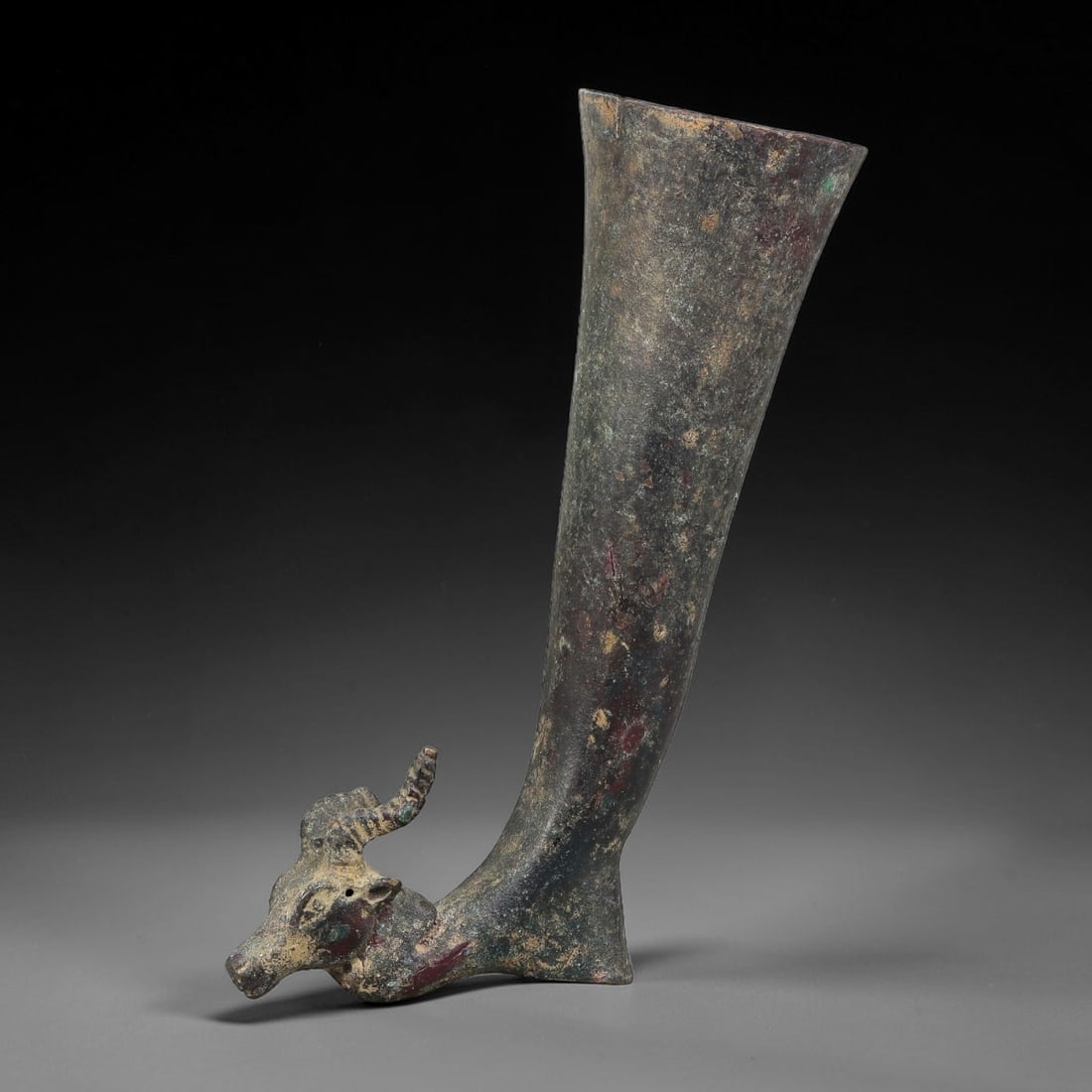 Ancient Achaemenid Persian Bronze Rhyton (c.550-330 BCE), 96AK: This ancient Achaemenid bronze rhyton features a bovid protome at its base, formed with characteristic period casting techniques. The vessel body tapers upward to a flared open rim, with heavy aged su
