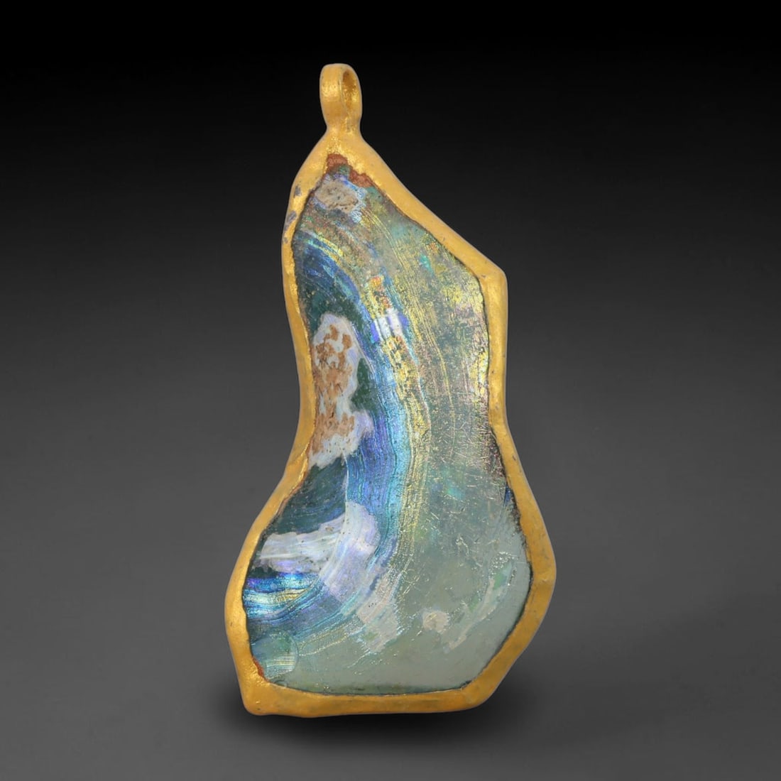 Ancient Roman Glass Slag in Modern Gilt-Edge Pendant, 57AK: This contemporary pendant is crafted from ancient Roman glass slag, featuring a fragmented, iridescent glass surface with weathered patina. The irregular form is bordered by a subtle gilt frame, added