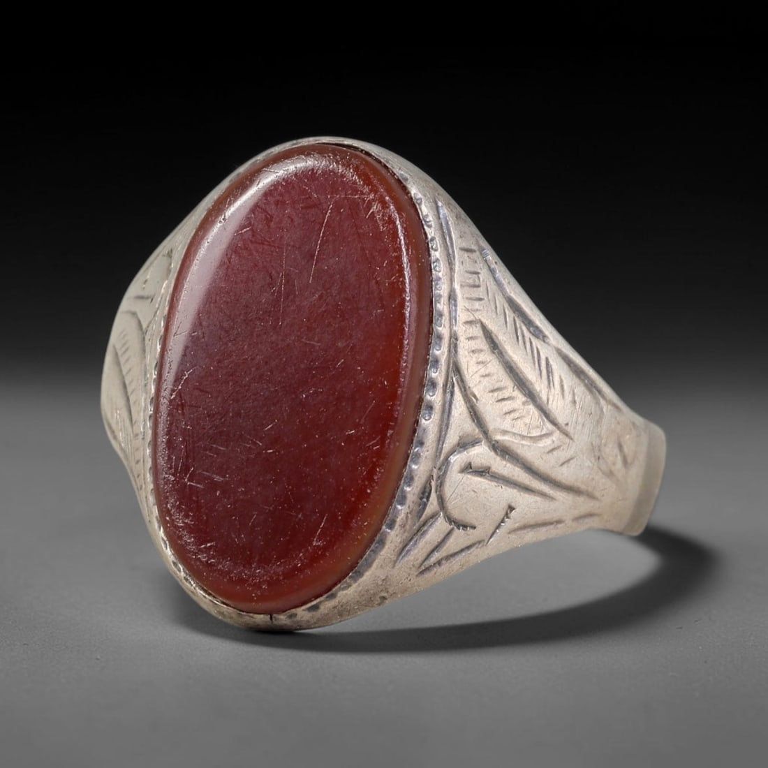 Antique Ottoman Carnelian Oval Cabochon Floral Engraved Silver Ring, 17AL: Silver ring of the Ottoman period set with an oval cabochon carnelian in simple bezel mounting. The shoulders are decorated with finely engraved foliate motifs. No hallmarks present. Ring size 9 US. S