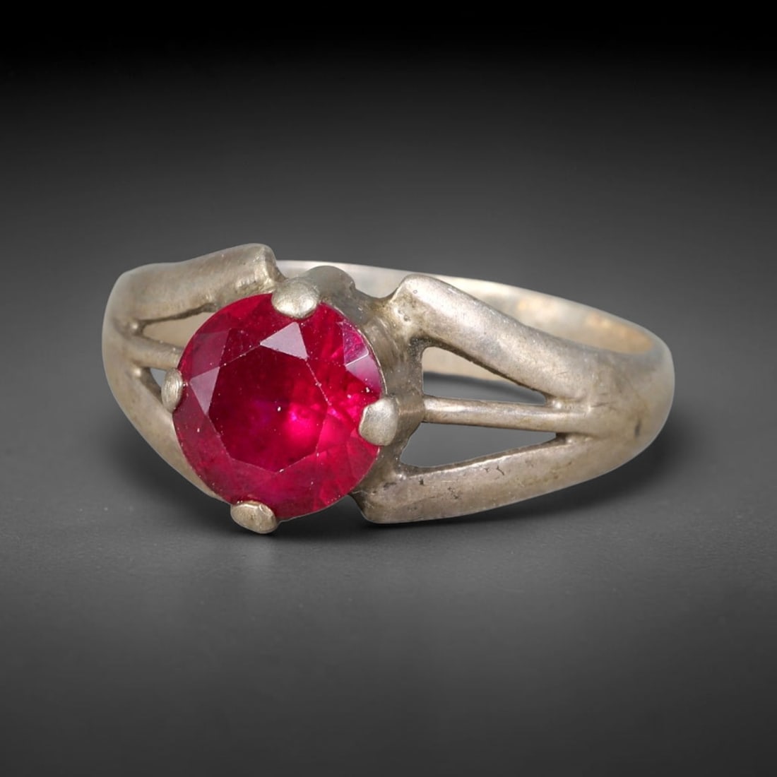 Antique Ottoman Ruby Four Prong Openwork Split Shank Silver Ring, 31AL: Silver ring of the Ottoman period set with a round faceted ruby secured by four metal prongs, featuring openwork split shoulders. Marked with 925 hallmark. Ring size 9 US. Surface patina and age-relat