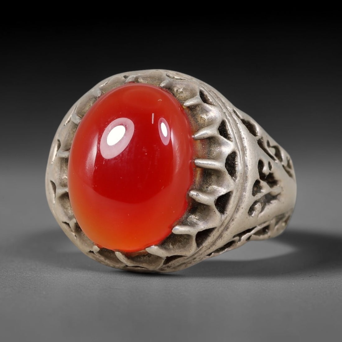 Antique Ottoman Carnelian Pierced Openwork Bezel Silver Ring, 13AL: Silver ring of the Ottoman period set with an oval cabochon carnelian, encased within an elaborate pierced openwork bezel and shank. No hallmarks present. Ring size 8.75 US. Surface patina and age-rel