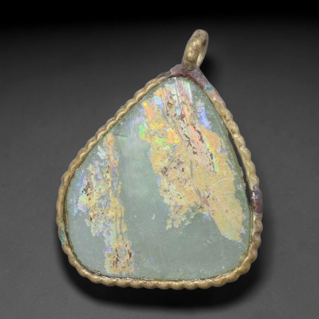 Ancient Roman Glass Slag in Modern Gilt-Edge Pendant, 78AK: This contemporary pendant is crafted from ancient Roman glass slag, featuring a fragmented, iridescent glass surface with weathered patina. The irregular form is bordered by a subtle gilt frame, added