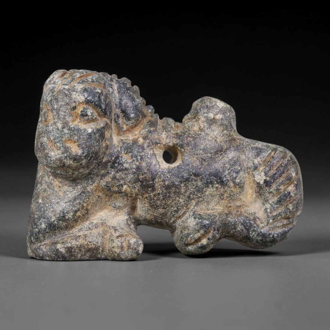 Ancient Neo-Hittite / Anatolian Bronze Age Sphinx-Form Stone Amulet (2000-700 BCE), 73AJ: This miniature carved dark stone sphinx-form wearable amulet originates from Neo-Hittite / Anatolian Bronze Age cultural tradition, serving as a protective talisman merging human and feline iconograph