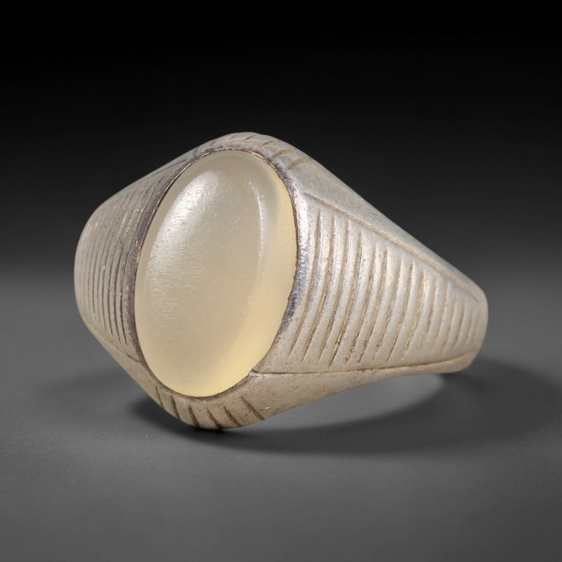 Antique Ottoman Moonstone Parallel Line Engraved Silver Ring, 20AL: Silver ring of the Ottoman period set with an oval cabochon moonstone, mounted within a simple bezel. The ring head and shoulders are decorated with parallel linear engraved motifs. No hallmarks prese