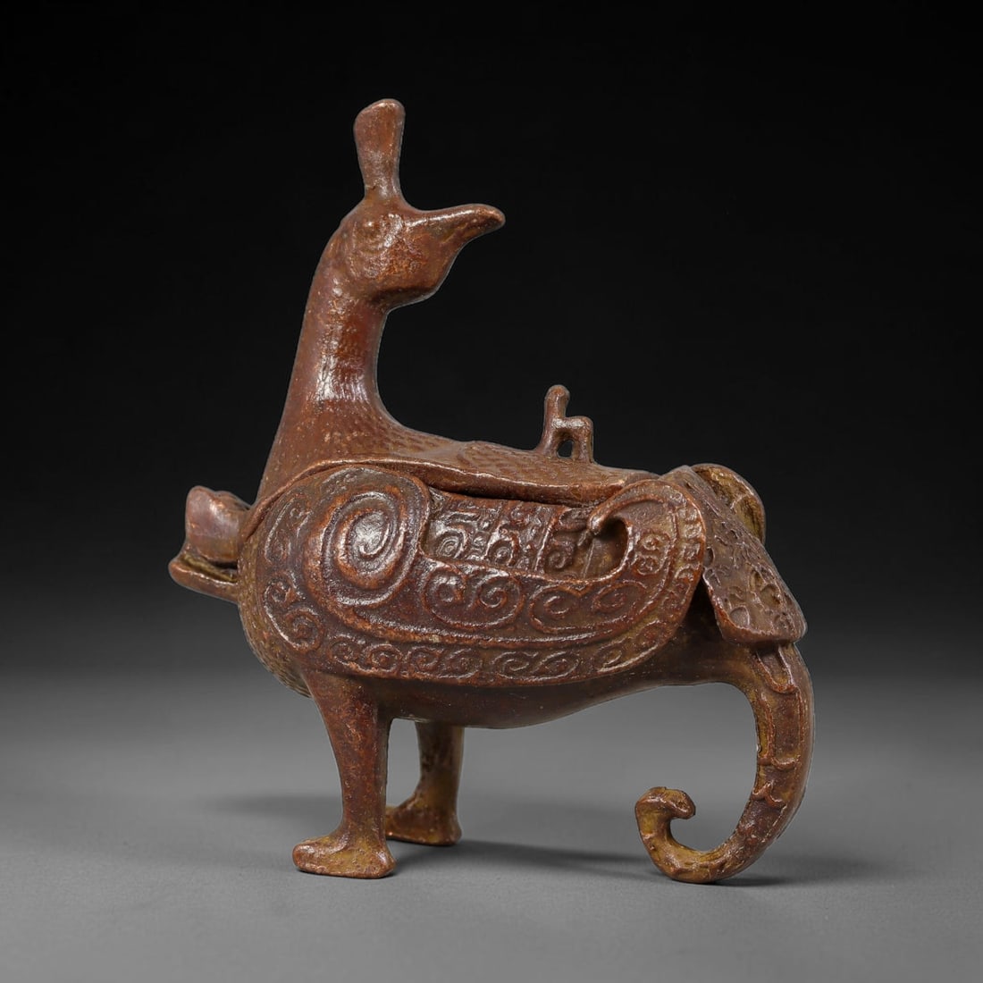 A Chinese Bronze Phoenix-Form Lidded Censer, 15AD: Cast in bronze, this figural censer is modelled as a stylized phoenix standing upon sturdy legs, with raised crest, gracefully curved neck and elaborate scrolling tail. The body functions as the main 