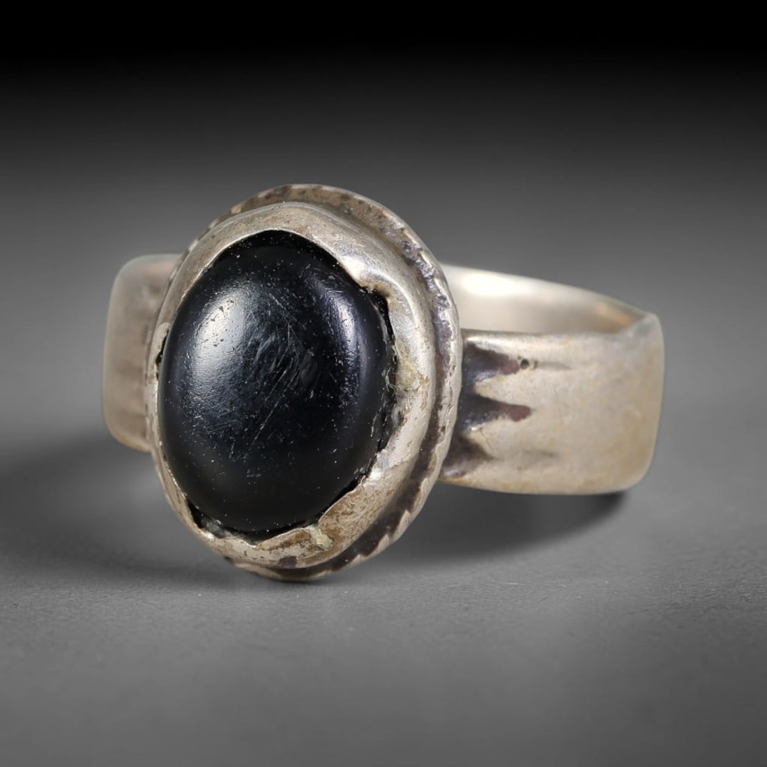 Antique Ottoman Black Onyx Layered Bezel Silver Ring, 40AL: Silver ring of the Ottoman period set with an oval cabochon black onyx mounted within a raised layered bezel. The wide flat shank retains hand-wrought surface texture. No hallmarks present. Ring size 