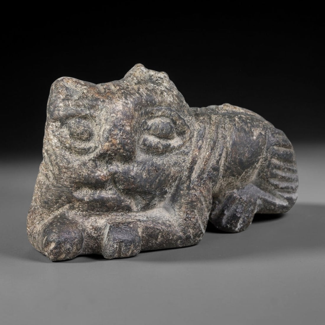 Ancient Sasanian Persian Schist Recumbent Feline Amulet (224-651 CE), 49AJ: Talismanic schist stone carving representing a recumbent feline creature, executed in Sasanian Persian sculptural idiom. Bold deep incised lines render facial features, paws and striped tail, embodyin