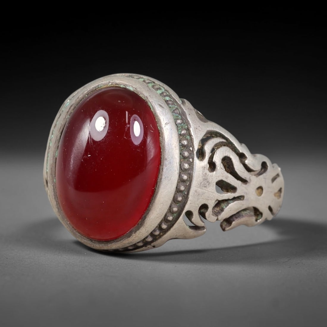 Antique Ottoman Carnelian Pierced Openwork Shank Silver Ring, 18AL: Silver ring of the Ottoman period set with an oval cabochon carnelian within a dotted decorated bezel. The ring shoulders feature elaborate pierced openwork ornamentation. Marked with 925 hallmark. Ri