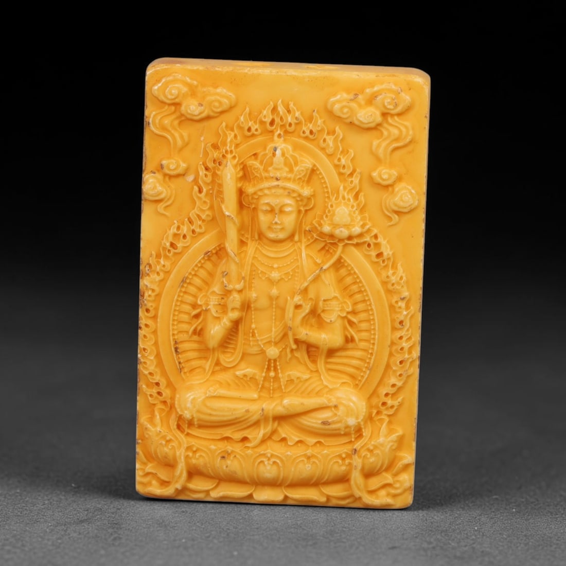 A Chinese Manjushri Deity Carved Tagua Nut Pendant Amulet, 96BC: Carved from tagua nut, this rectangular tablet-form amulet is worked in high relief. Manjushri is seated in full lotus posture upon an ornate lotus pedestal, grasping the flaming wisdom sword in one h
