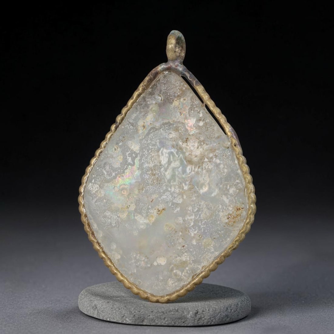 Ancient Roman Glass Slag in Modern Gilt-Edge Pendant, 73AK: This contemporary pendant is crafted from ancient Roman glass slag, featuring a fragmented, iridescent glass surface with weathered patina. The irregular form is bordered by a subtle gilt frame, added