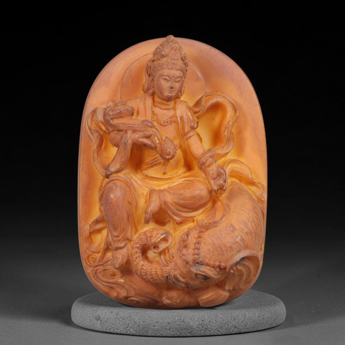 A Chinese Samantabhadra Deity Carved Tagua Nut Pendant Amulet, 1AD: Carved from tagua nut, this oval tablet-form amulet is executed in high relief. The Bodhisattva Samantabhadra is depicted in a relaxed seated pose atop a detailed elephant mount, holding a ruyi sceptr