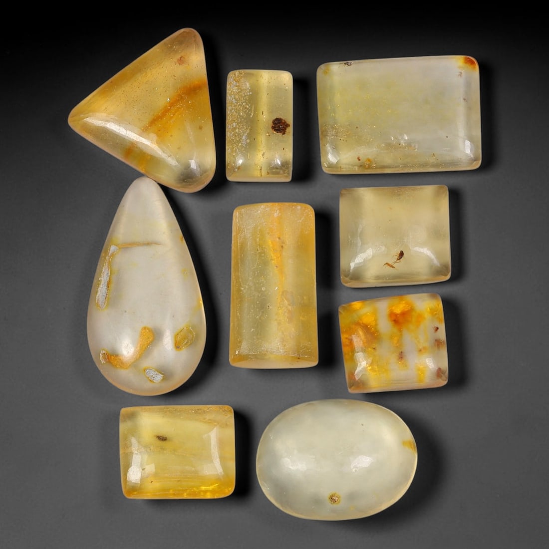 53.38ct Natural Baltic Amber Polished Cabochon Parcel Lot, 28AJ: This parcel features rounded rectangle cabochon baltic amber pieces with warm translucent golden-yellow to honey-gold tones. Smooth polished domed surfaces expose numerous preserved small insect fragm