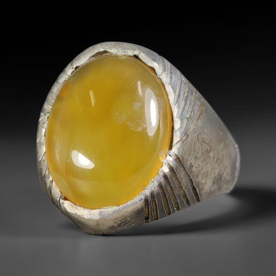 Antique Ottoman Yellow Agate Domed Cabochon Engraved Bezel Silver Ring, 37AL: Silver ring of the Ottoman period set with a large domed oval cabochon yellow agate, mounted within a bezel decorated with angled linear incised carving. The wide solid shank retains hand finished tex