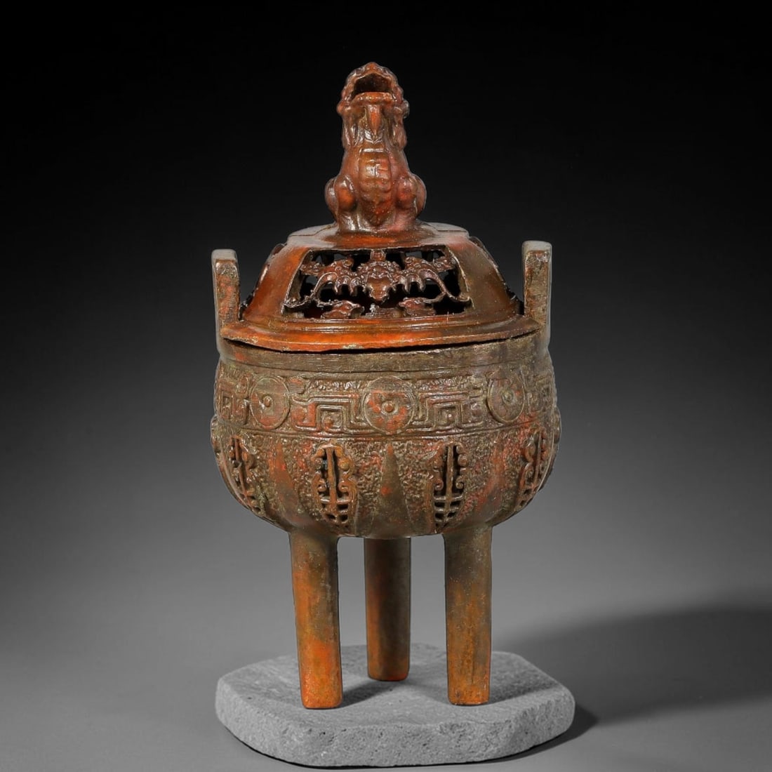 A Chinese Bronze Tripod Censer with Mythical Beast Finial, 92AD: Cast bronze tripod censer featuring two upright rectangular rim handles, supported by three tall cylindrical legs. The pierced open-work lid is surmounted by a seated mythical beast finial, with bat-m