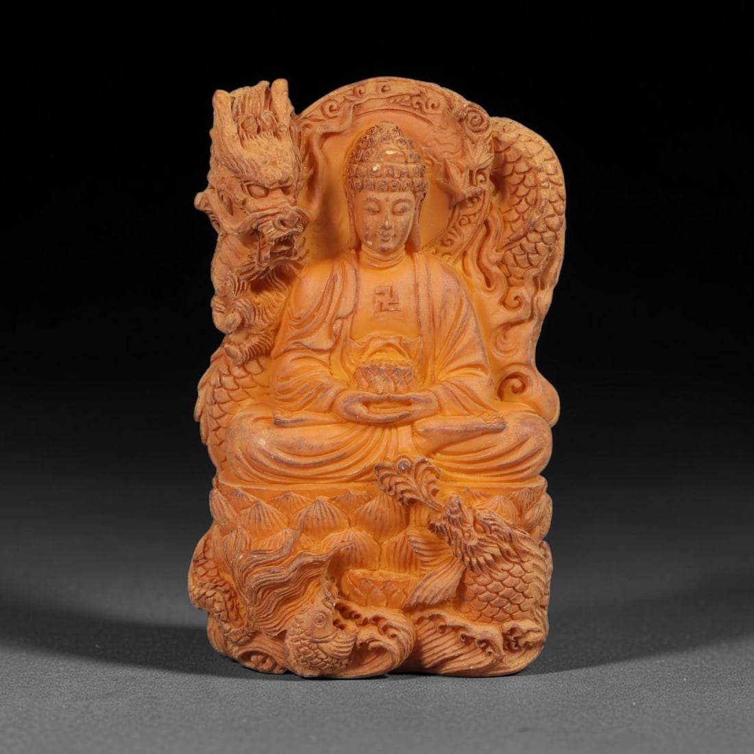A Chinese Buddha Deity Carved Tagua Nut Pendant Amulet, 100BC: Carved from tagua nut, this tablet-form amulet is executed in high-relief. The central figure depicts a Buddha seated in lotus position upon a multi-petalled lotus base, hands held in a meditative ges