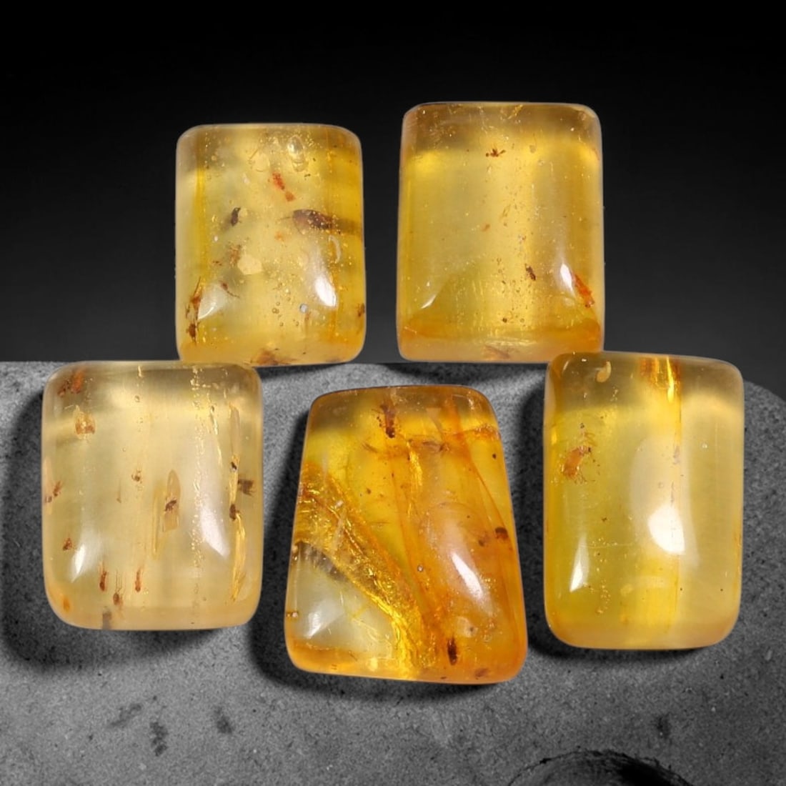 35.36ct Natural Baltic Amber Polished Cabochon Parcel Lot, 56EY: This parcel features rounded rectangle cabochon baltic amber pieces with warm translucent golden-yellow to honey-gold tones. Smooth polished domed surfaces expose numerous preserved small insect fragm