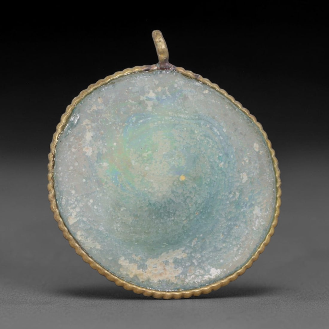 Ancient Roman Glass Slag in Modern Gilt-Edge Pendant, 71AK: This contemporary pendant is crafted from ancient Roman glass slag, featuring a fragmented, iridescent glass surface with weathered patina. The irregular form is bordered by a subtle gilt frame, added
