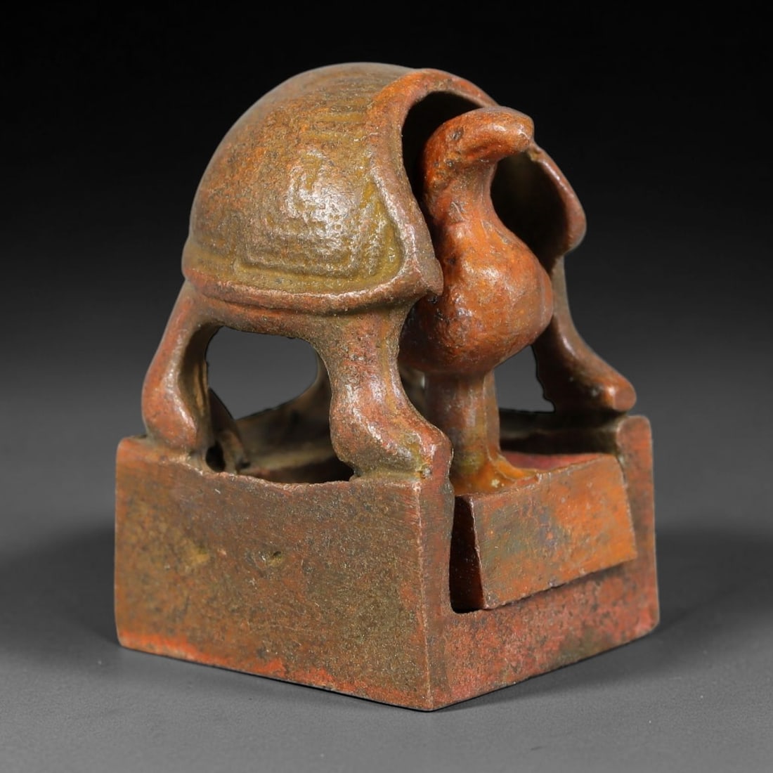 An Antique Chinese Bronze Interlocking Turtle Seal, 44AL: Cast in bronze with mottled reddish-brown and olive patina, the object consists of a square outer seal matrix topped by a hollow turtle shell finial, and a removable avian-form inner seal that nests w