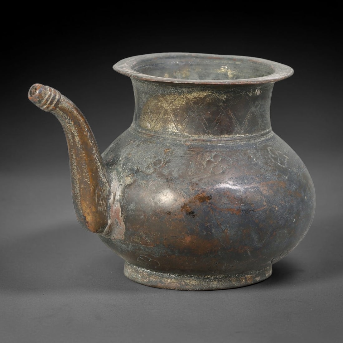 Ancient Seljuk Period Bronze Ewer (c.1037-1194 CE), 51AL: Cast bronze ewer with deep mottled brown and dark patina, showing areas of wear and faint surface deposits. It has a flared wide rim, short tapered neck decorated with incised lattice ornamentation, a