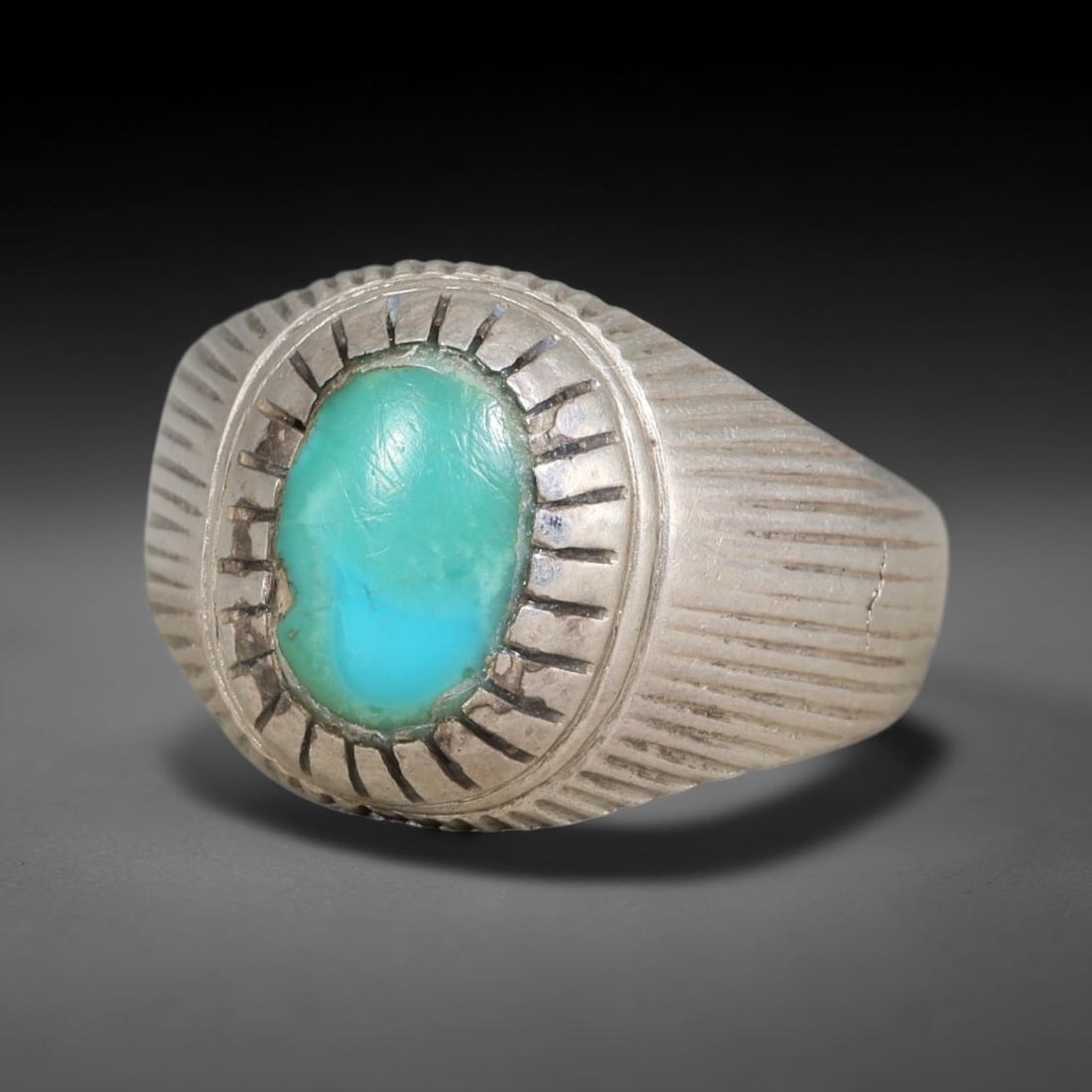 Antique Ottoman Turquoise Oval Cabochon Radiating Incised Silver Ring, 25AL: Silver ring of the Ottoman period set with an oval cabochon turquoise, mounted within a double layered radiating incised bezel. Linear engraved detailing extends outward across the wide ring face. Mar