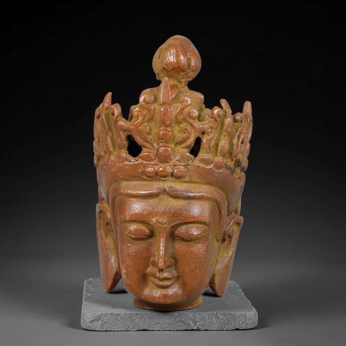 A Tibetan Bronze Crowned Deity Head Finial, 39AD: Cast in bronze, this fragmentary finial depicts a deity head with serene closed-eyed facial expression, smooth modelled features and urna upon the forehead. The elaborate openwork royal crown is decor